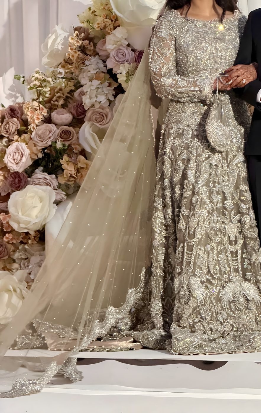 Silver hand-embroidered bridal gown with a beaded veil, worn with a matching pouch