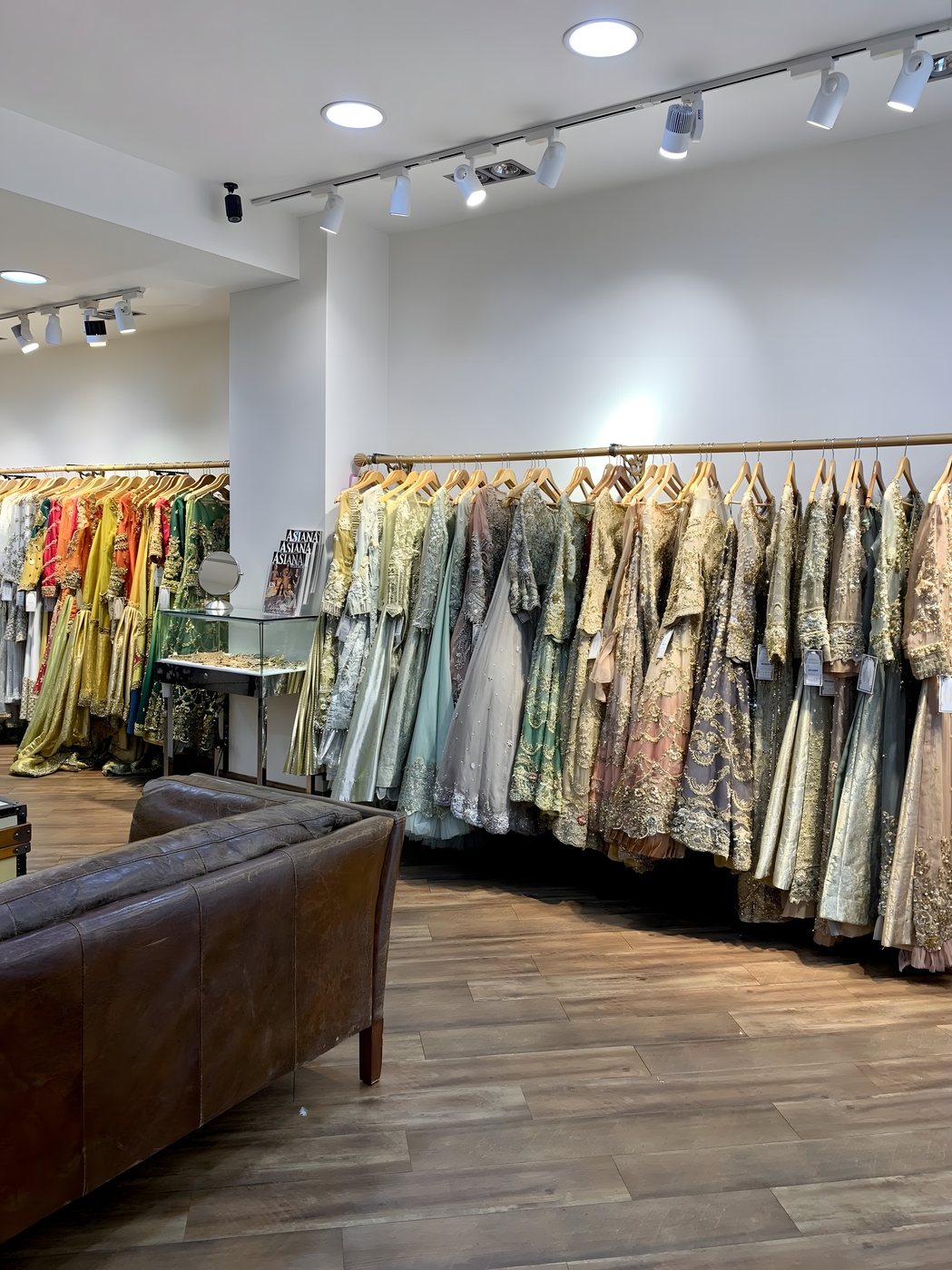 Rails of hand-embroidered bridal lehengas in sage, gold and blush inside the Tehxeeb London showroom